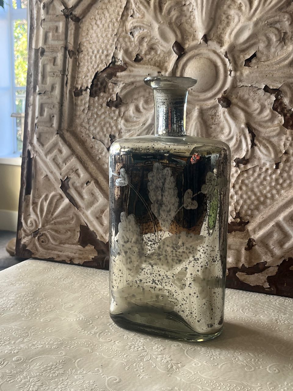 Vintage silver mercury glass bottle with etched floral pattern,