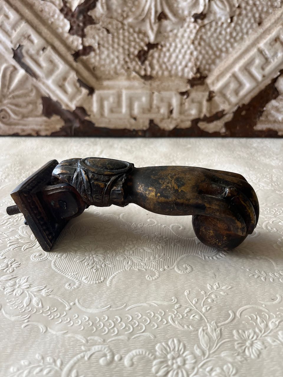 "Antique French cast iron 'Hand of Fatima' door knocker with a decorative ruffled cuff, holding a ball, can mounted on a rustic wooden door. or modern door"